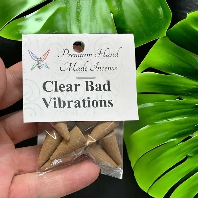Crystal Fairy Patch Clear Bad Vibrations premium hand-made cone incense in a clear plastic bag against a green leaf background.