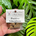Crystal Fairy Patch Positive Vibrations premium hand-made cone incense in a small clear bag held against green monstera leaves.