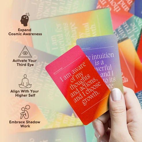 Hand holding two cards: Hand holding red and purple Spiritual Growth Affirmations cards about self-awareness and intuition.