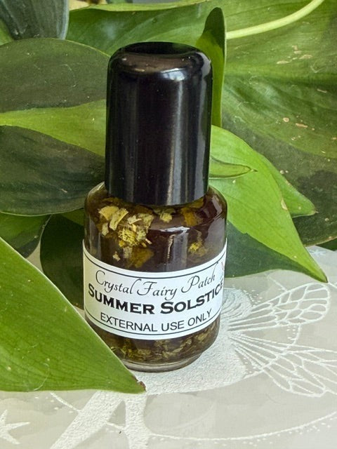Crystal Fairy Patch Summer Solstice ritual oil in a small glass bottle with botanical herbs, set against green leaves.